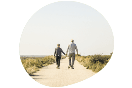 Elderly couple holding hands walking down a countryside road