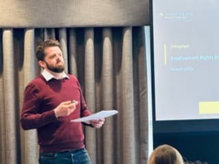 Matt McDonald of Shakespeare Martineau  presents a document beside a screen displaying "Employment Rights" and "March 2023" in a conference room.