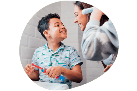 Mother and child brushing teeth together and smilingd