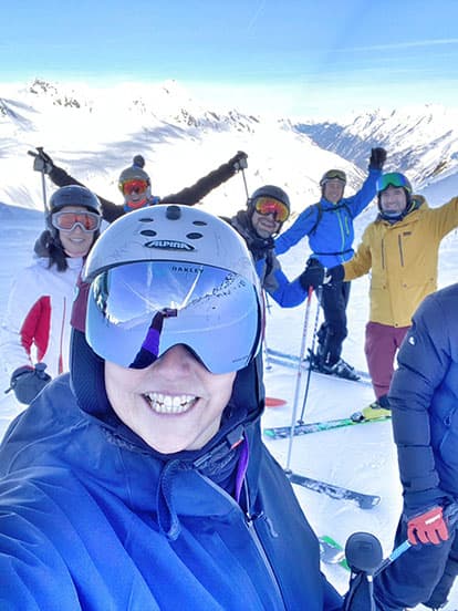 A group of Denplan dentists with their arms in air and smiling on a snowy mountain side