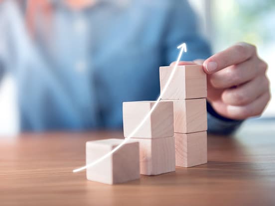 Person using small wooden blocks to represent an upward trend on a graph