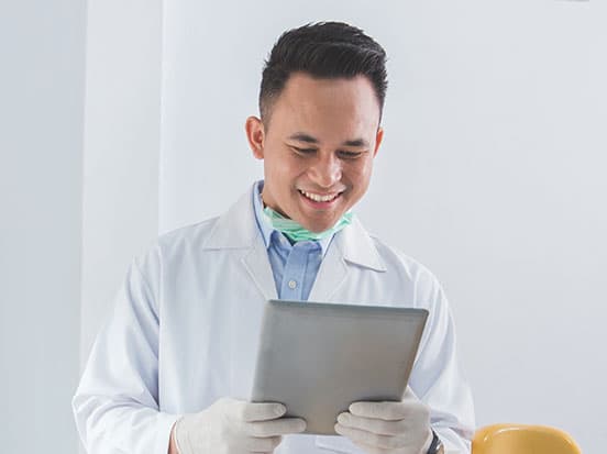 Smiling dentist using tablet in clinic
