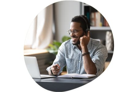 Man wearing headset sitting by a desk with a laptop