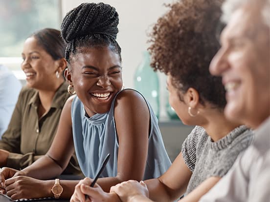 Woman sat at table with colleagues and all smiling