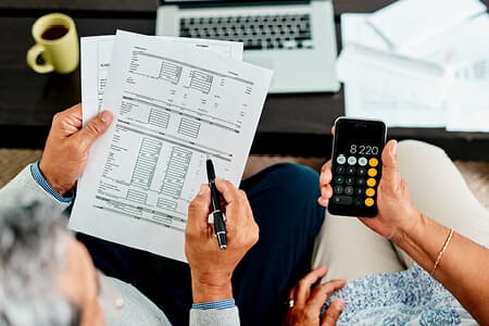 Two people holding financial balance sheet and calculator