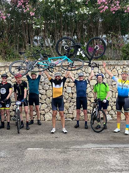 Denplan dentists posing with road bikes beside a stone brick wall